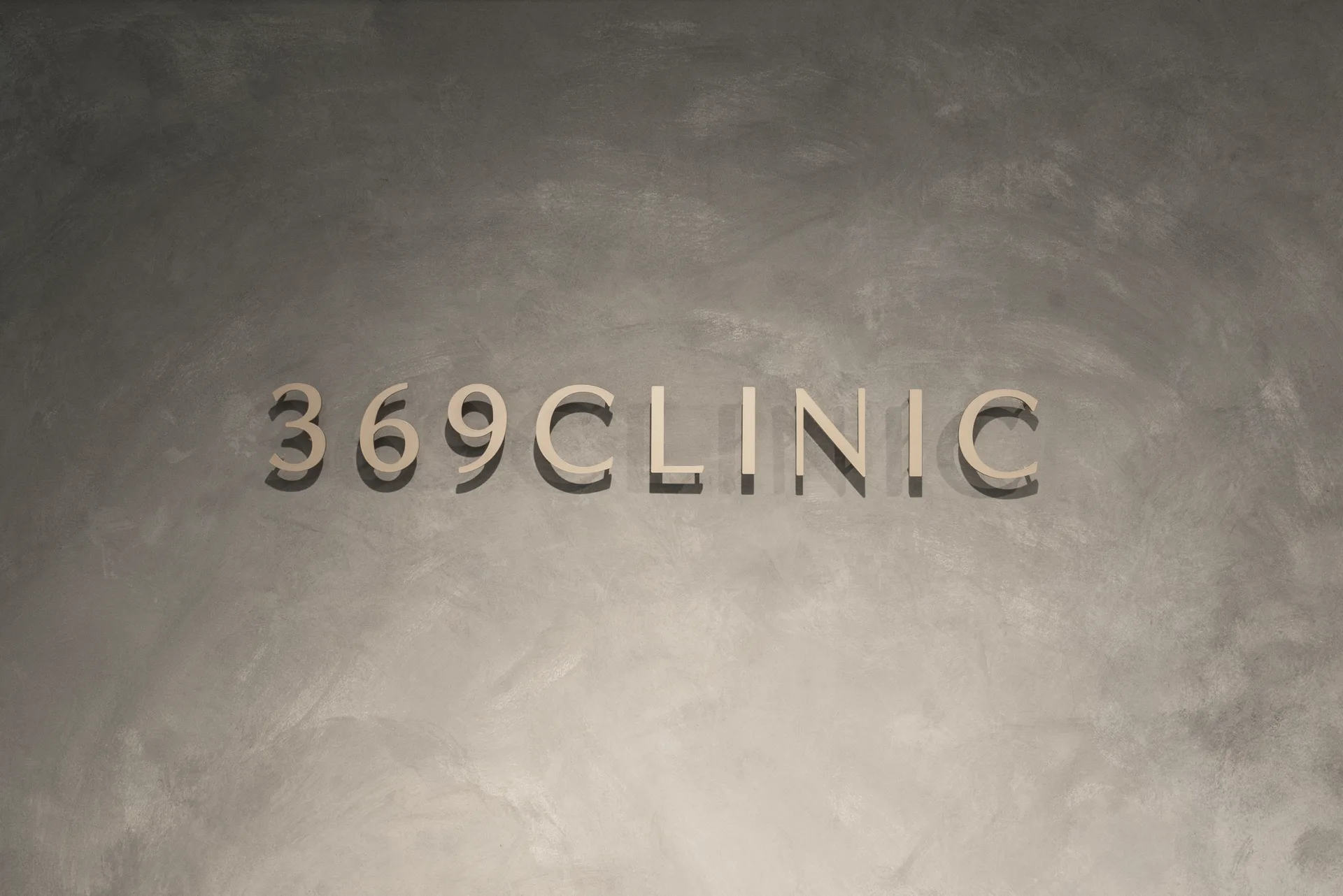 The gold 369CLINIC logo set against the mortar wall